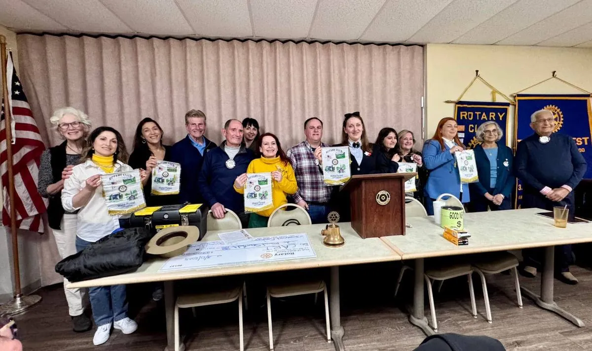 Moldovan delegates and Rotarians holding Rotary Club of Wake Forest banners at a club meeting