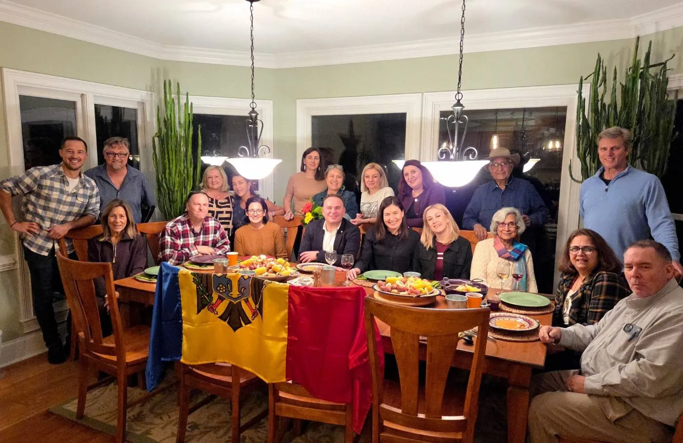 Delegates and Rotarians around a host family's dinner table draped with the Moldovan flag, set for a Low Country boil