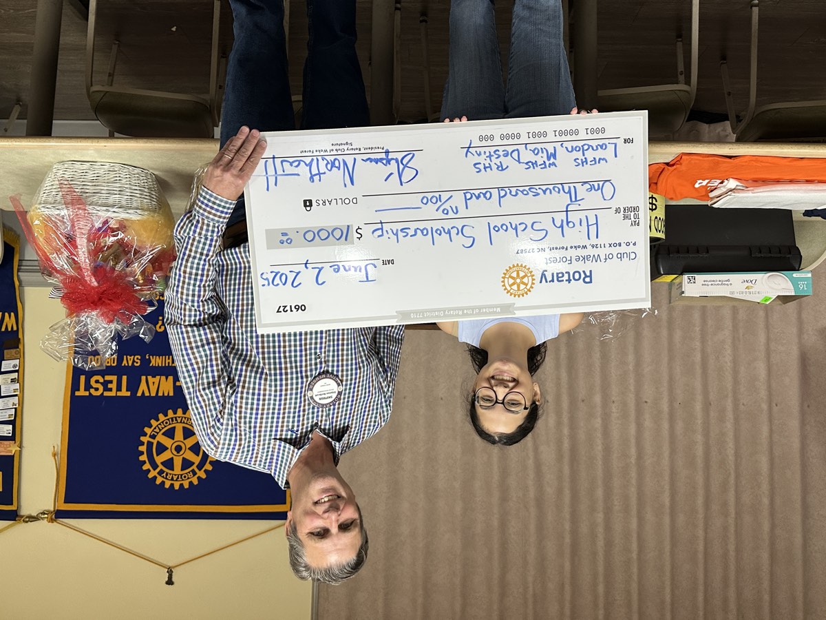 A graduating senior receives a $1,000 High School Scholarship check from a Rotary Club of Wake Forest member in 2025