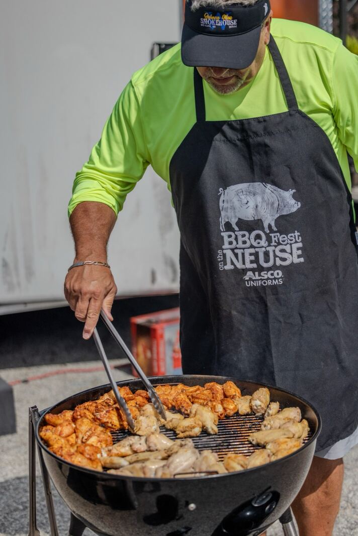 Cook-off competitor turning chicken wings on a kettle grill at the 2026 Cars & Carnivores festival